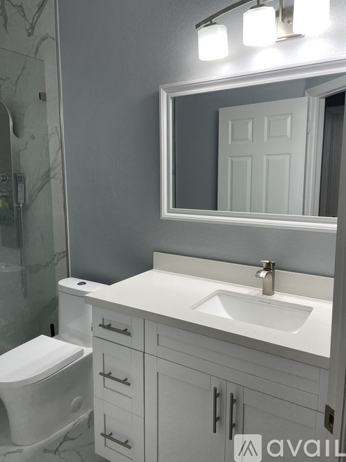 A white bathroom with a toilet, sink, and mirror.