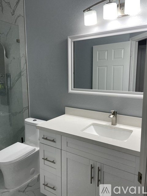 A white bathroom with a toilet, sink, and mirror.