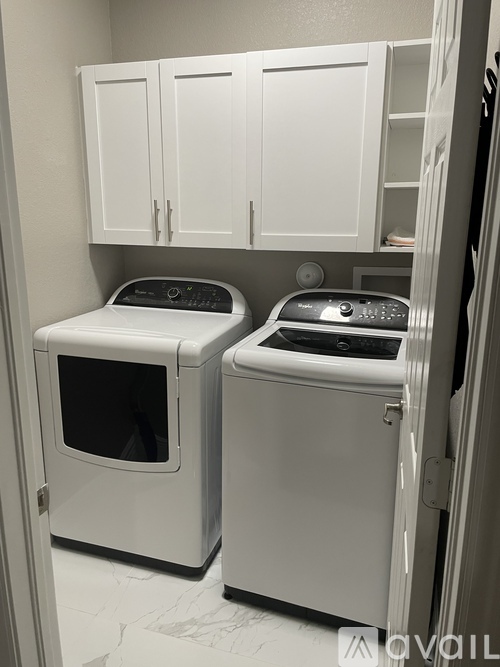 A white dishwasher and dryer are in a small kitchen.