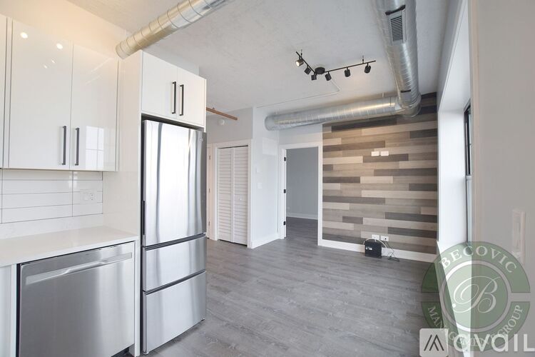A modern kitchen with white cabinets and a wooden accent wall.
