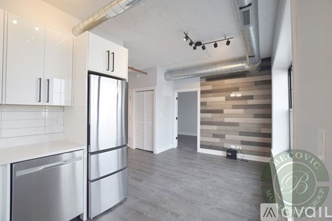 A modern kitchen with white cabinets and a wooden accent wall.