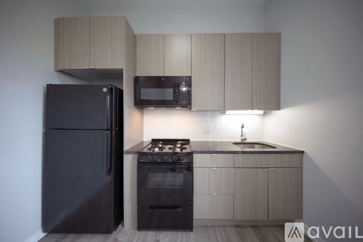 A kitchen with a black refrigerator, black oven, and black microwave.