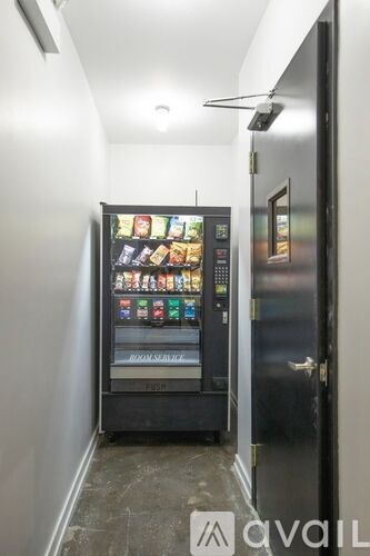 A vending machine with a variety of snacks and drinks is located in a narrow hallway.