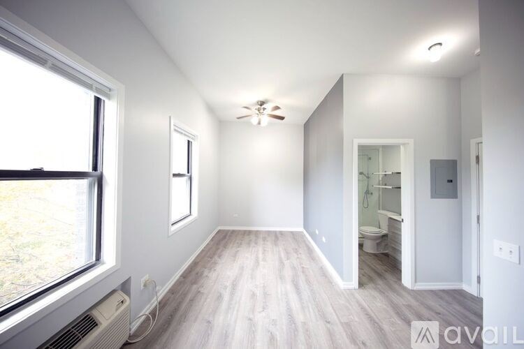 A spacious room with a window, a ceiling fan, and a door leading to another room.