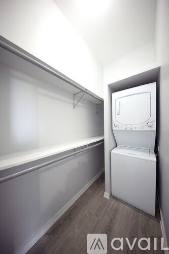 A white washing machine is in a small room with a grey wall.