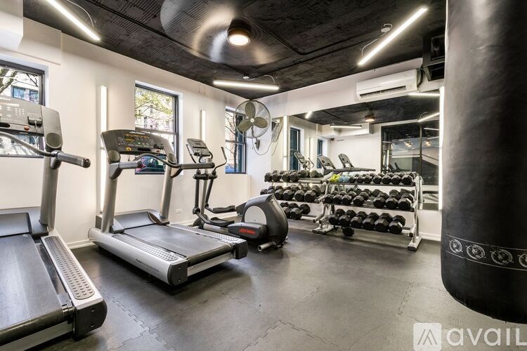 A gym with treadmills, elliptical machines, and a punching bag.