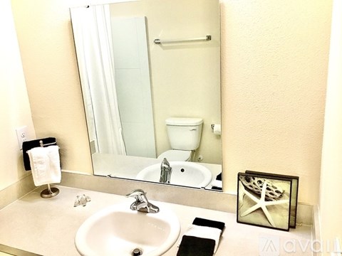 A bathroom with a sink, mirror, toilet, and a small picture frame.