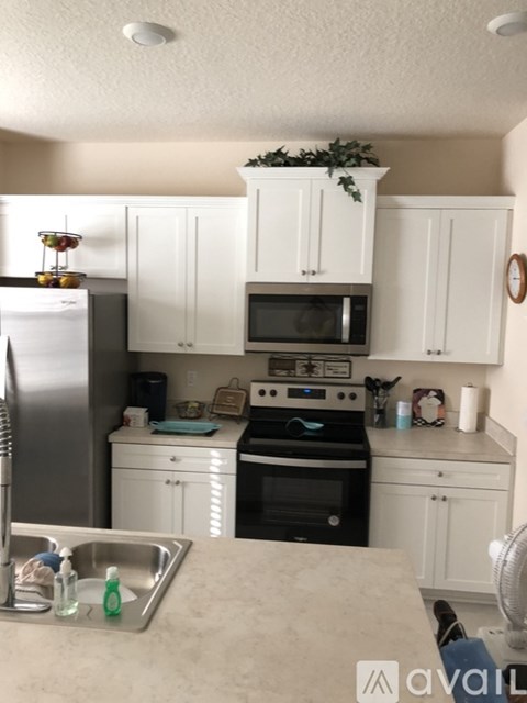 A kitchen with white cabinets and a black stove top oven.