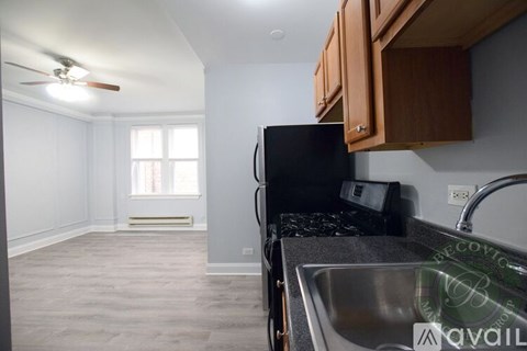 A kitchen with a black fridge and a fan on the ceiling.