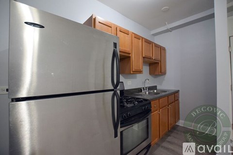 A stainless steel refrigerator is in a kitchen with wooden cabinets.