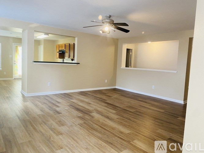 A spacious room with wooden flooring and a ceiling fan.