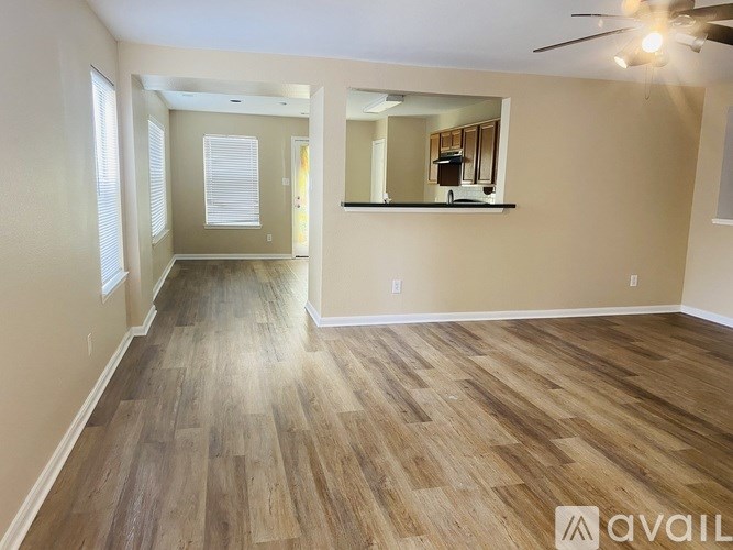 A spacious room with wooden flooring and a ceiling fan.