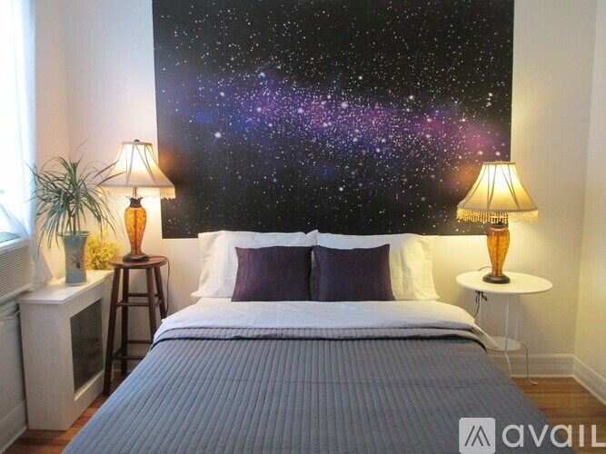 A bedroom with a large galaxy mural on the wall.