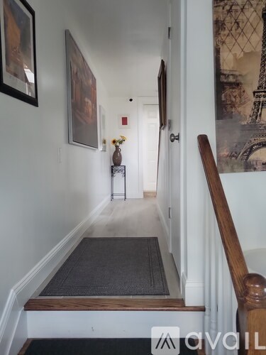 A hallway with a black mat on the floor and a wooden banister.