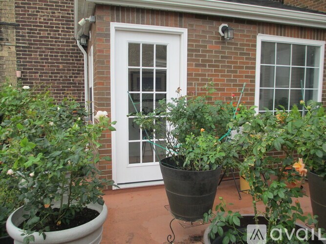A white door is on the left of two windows on a brick building.