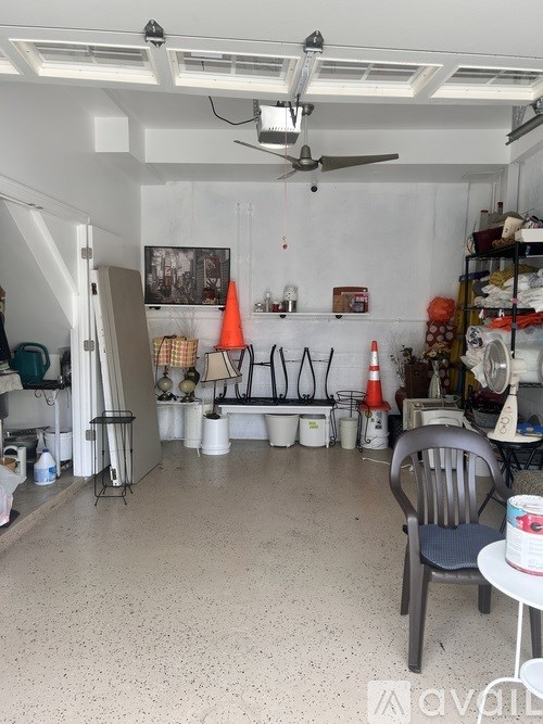 A room with a chair, a table, and a fan.