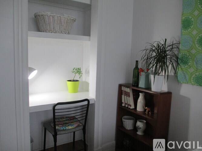 A room with a chair, a table, a potted plant, and a shelf with various objects.
