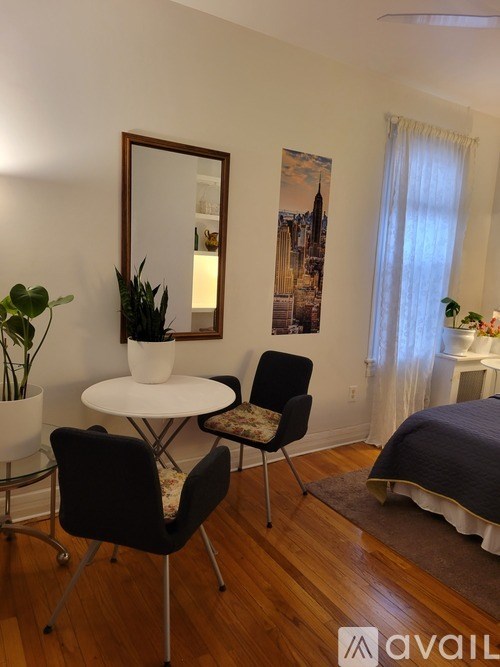 A bedroom with a bed, a table, a chair, and a mirror.