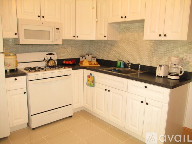 A kitchen with white cabinets and appliances.