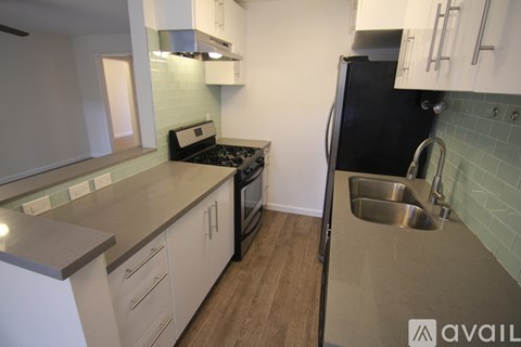 A kitchen with a black refrigerator and a stove top oven.