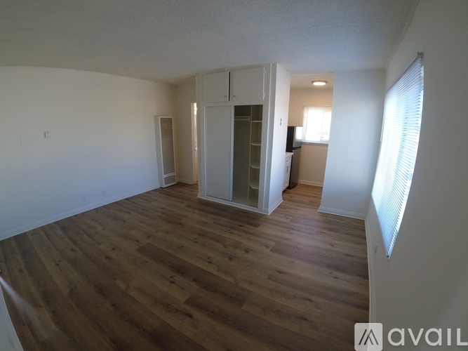 A room with wooden floors and white walls, with a doorway leading to another room.