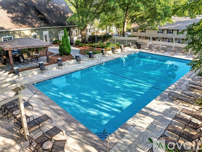 A large outdoor swimming pool surrounded by lounge chairs and umbrellas.