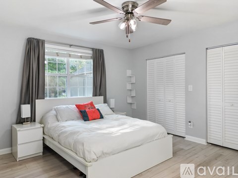 A bedroom with a white bed and a ceiling fan.