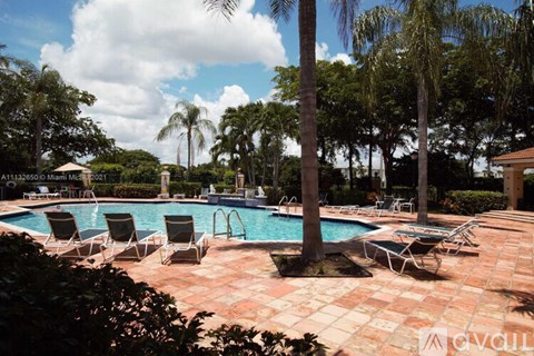 A pool surrounded by chairs and trees.