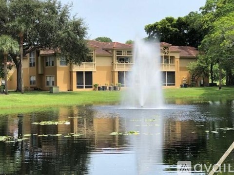 A fountain in the middle of a pond in front of a building.