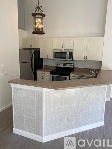 A kitchen with a white tiled island and a black stove top oven.