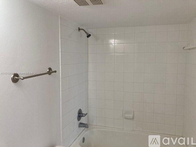 A white tiled shower with a silver shower head and hand held shower.
