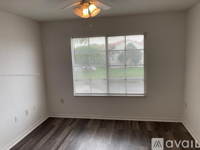 A room with a ceiling fan and a window with blinds.
