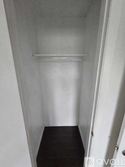A white hallway with a wooden floor and a white door.