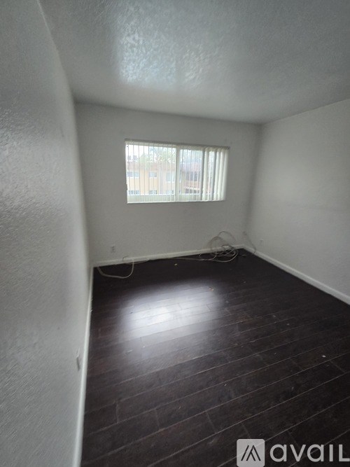 A room with a window and wooden flooring.