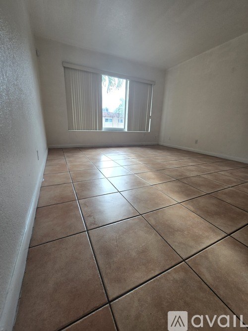A room with tiled flooring and a window with blinds.