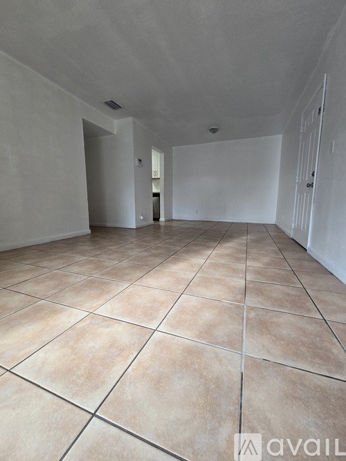 A spacious room with tiled flooring and white walls.