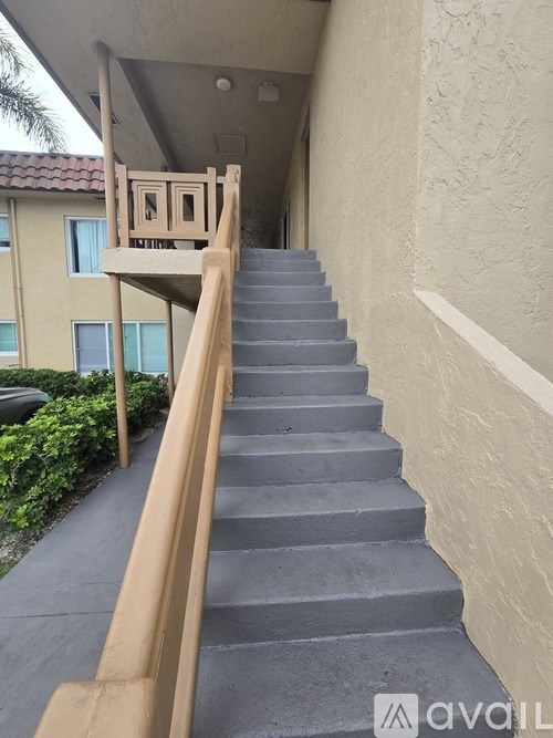 A staircase with a wooden handrail and grey steps.