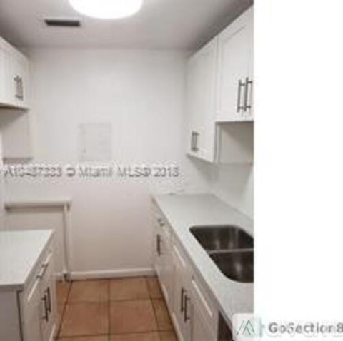 A kitchen with white cabinets and a white counter top.