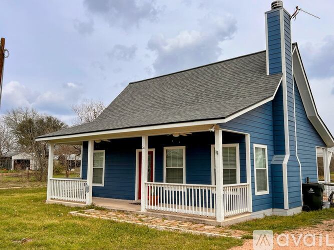 A blue house with a white porch and a chimney.