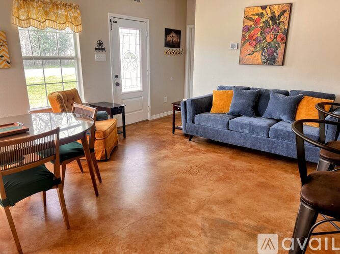 A living room with a blue couch and a dining table with chairs.