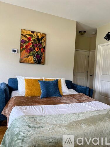 A bedroom with a large bed and a painting on the wall.