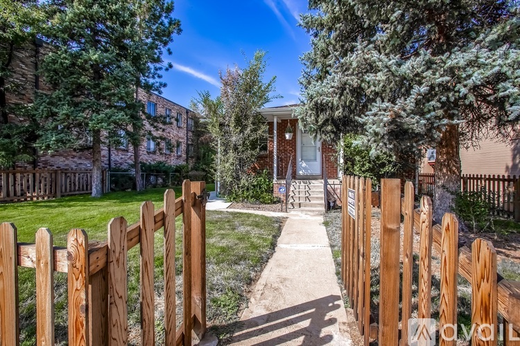 A wooden fence leads to a house entrance.