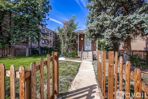 A wooden fence leads to a house entrance.