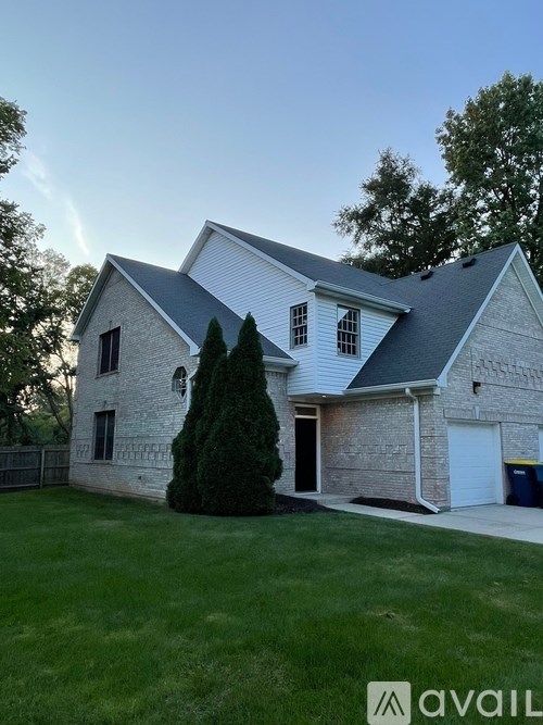 A house with a white garage door and a tree in front.