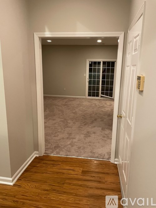 A room with a white door and a wooden floor.