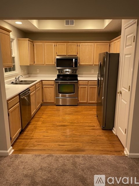 A kitchen with wooden cabinets and a black fridge.