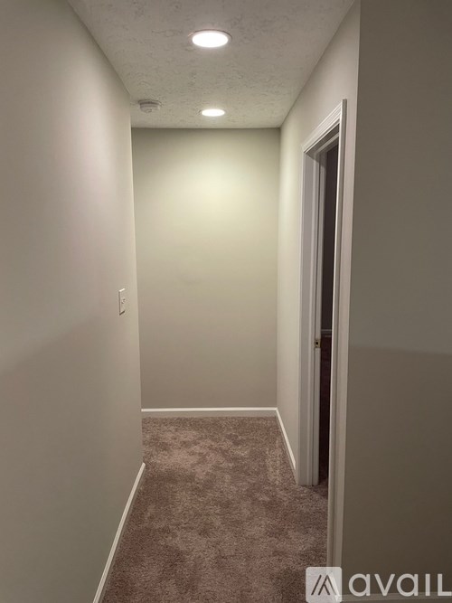 A hallway with a carpeted floor and white walls.