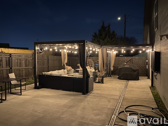 A cozy outdoor space with a bed and lights strung up.