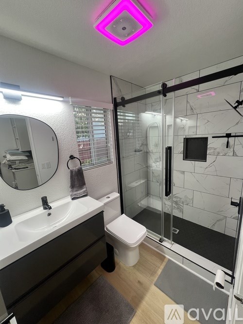 A white closet with clothes hanging and a mirror on the wall.