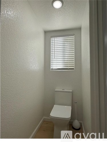 A small white toilet in a narrow bathroom.